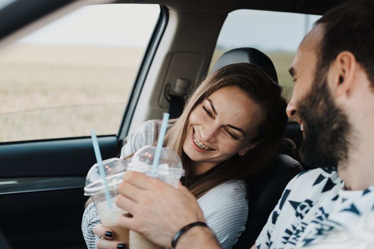 Happy couple with newborn baby sitting in car, smiling together